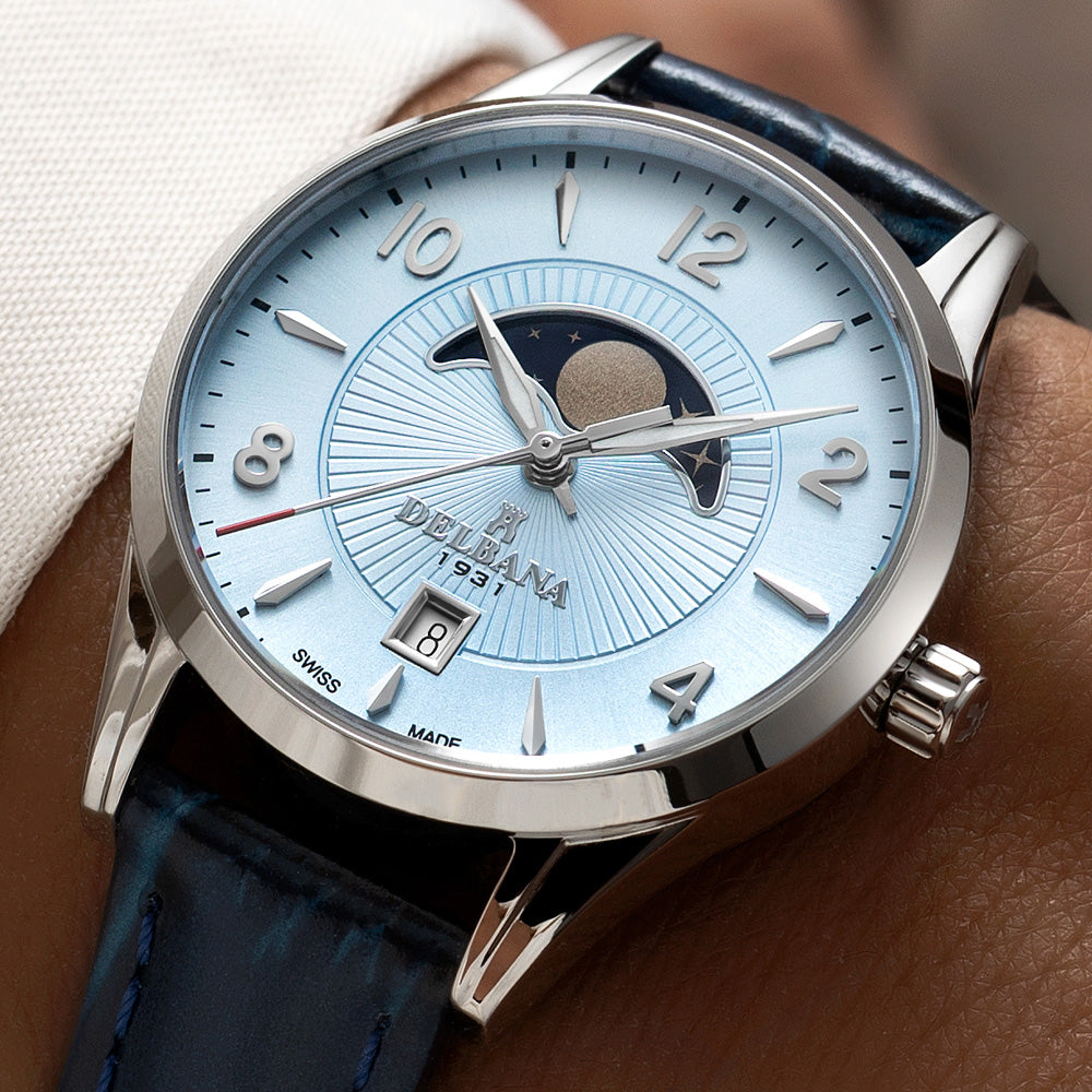 Delbana Lunetta stainless steel moonphase watch with light blue dial and navy blue leather strap on wrist close up