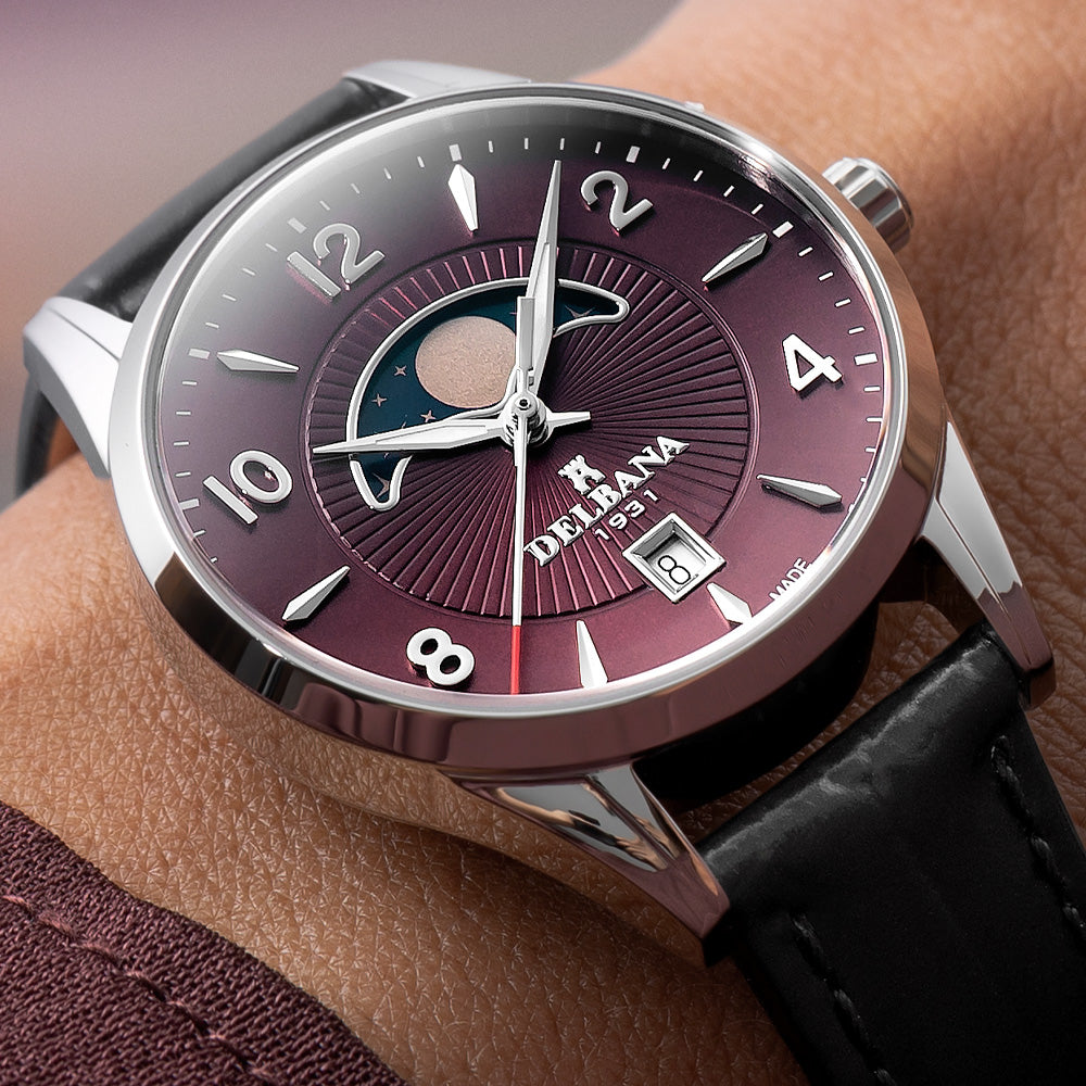 Delbana Lunetta stainless steel moonphase watch with burgundy dial and black leather strap on wrist close up