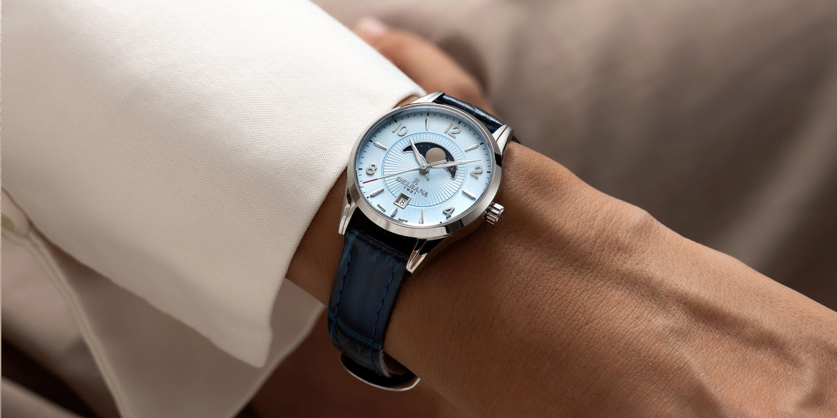 Delbana Lunetta stainless steel moonphase watch with light blue dial and navy blue leather strap on wrist