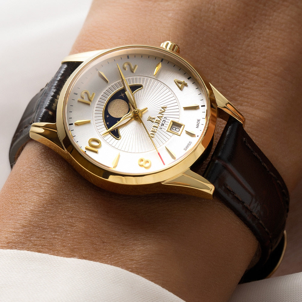 Delbana Lunetta stainless steel with yellow gold PVD moonphase watch with silver dial and brown leather strap on wrist close up